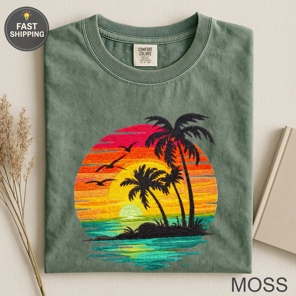 Green t-shirt with embroidered sunset, palm trees, and ocean scene.