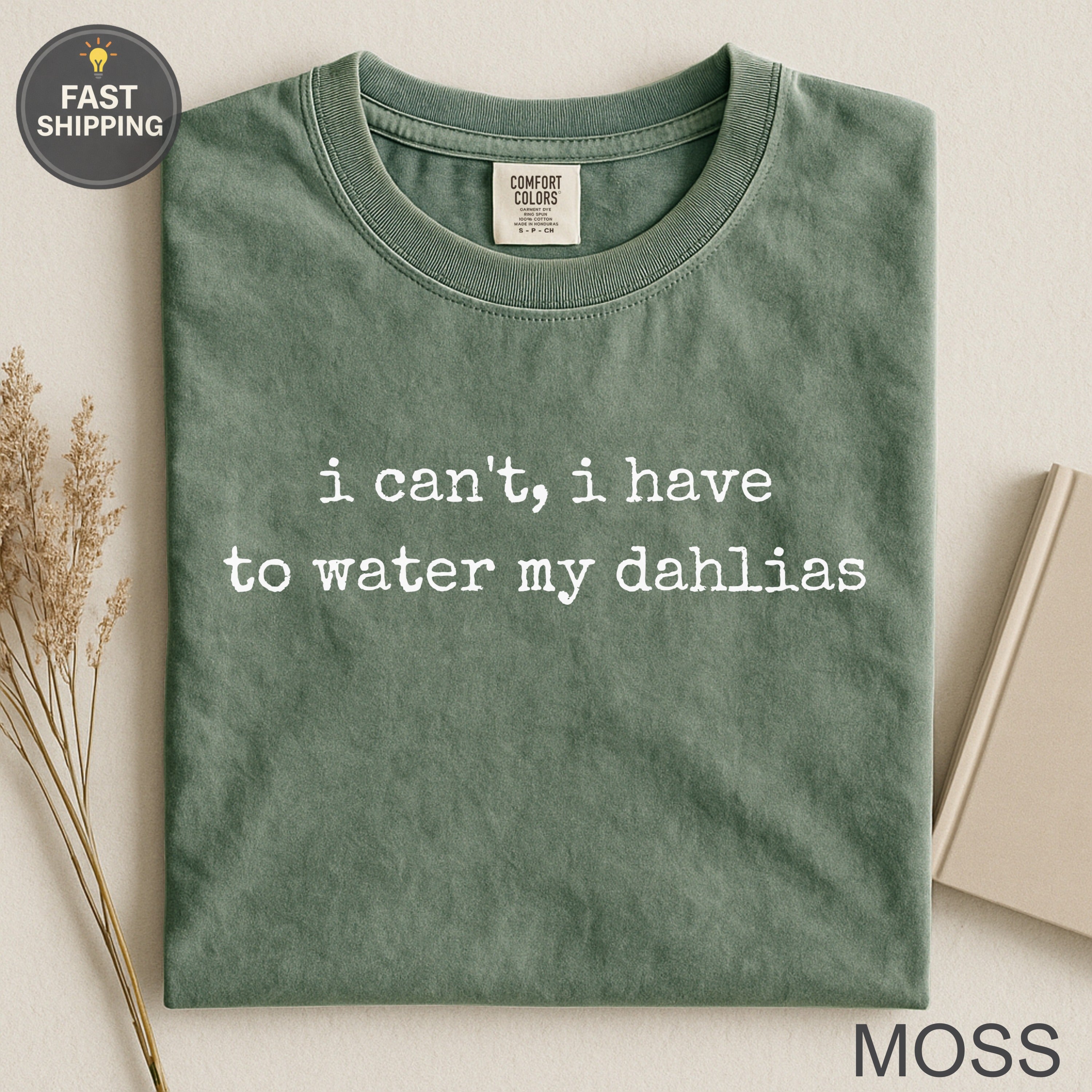 Green t-shirt with white text: "i can't, i have to water my dahlias".