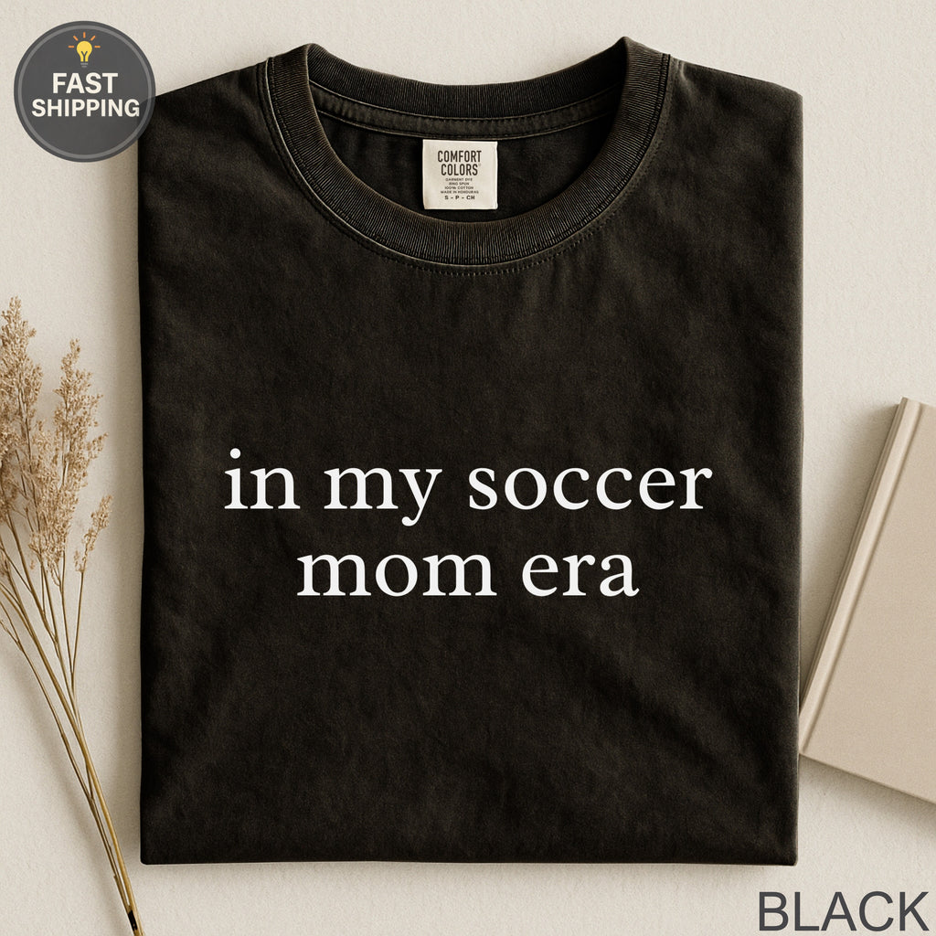 Black t-shirt with "in my soccer mom era" text in white.