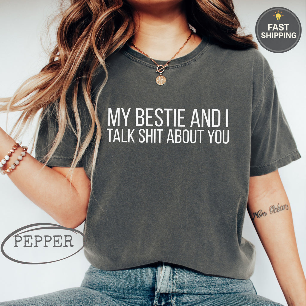 Dark gray t-shirt with white text "MY BESTIE AND I TALK SHIT ABOUT YOU".