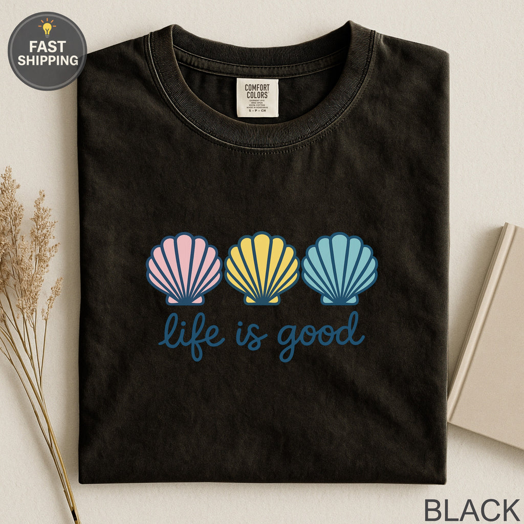 Black t-shirt with three colorful seashells and "life is good" text.