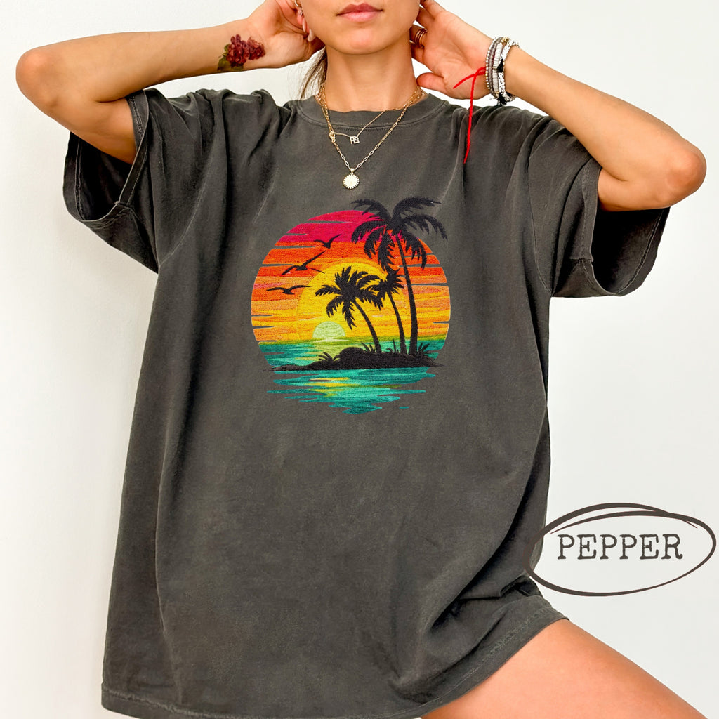 Black t-shirt with a sunset, palm trees, and ocean graphic.