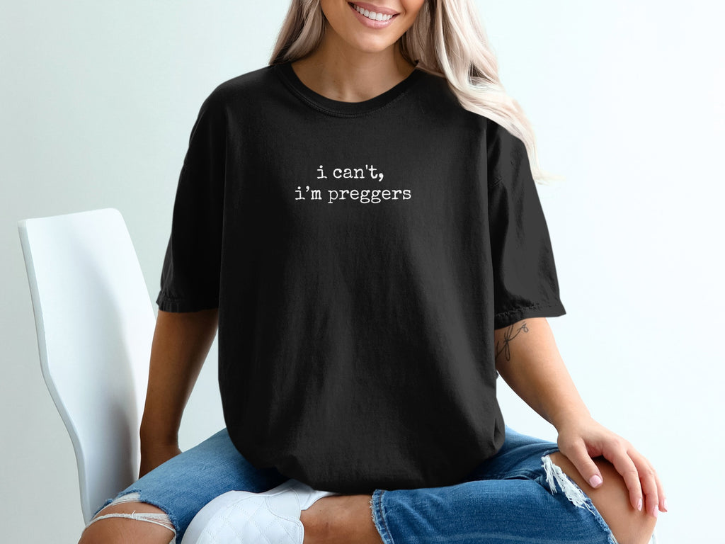 Black t-shirt with white text "I can't, I'm pregger" worn by a woman.