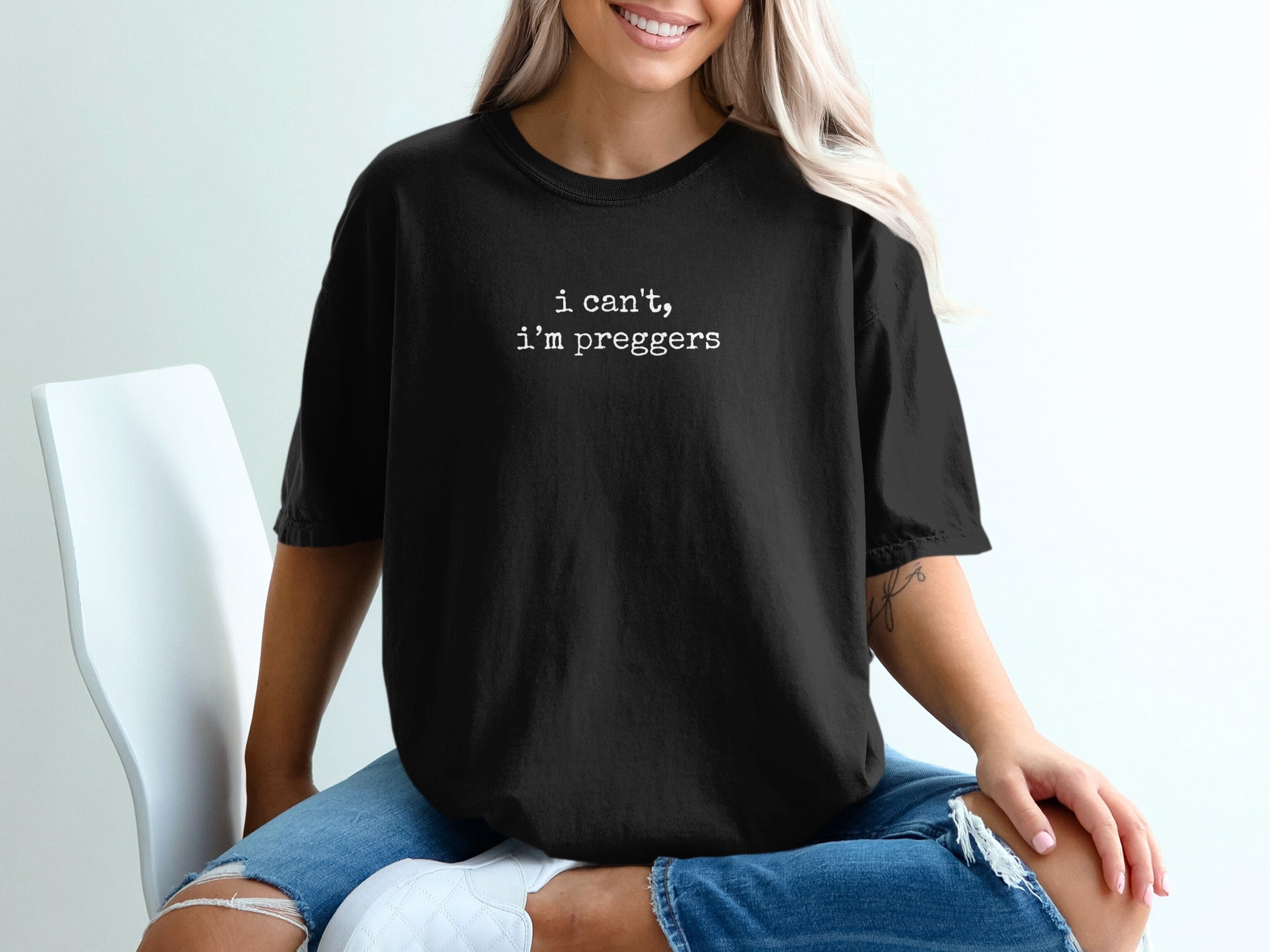 Black t-shirt with white text "I can't, I'm pregger" worn by a woman.
