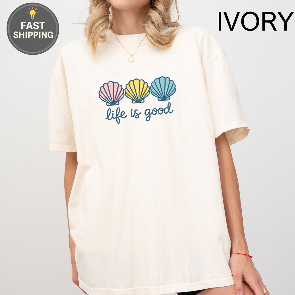 Cream t-shirt with pastel seashells and "life is good" text.