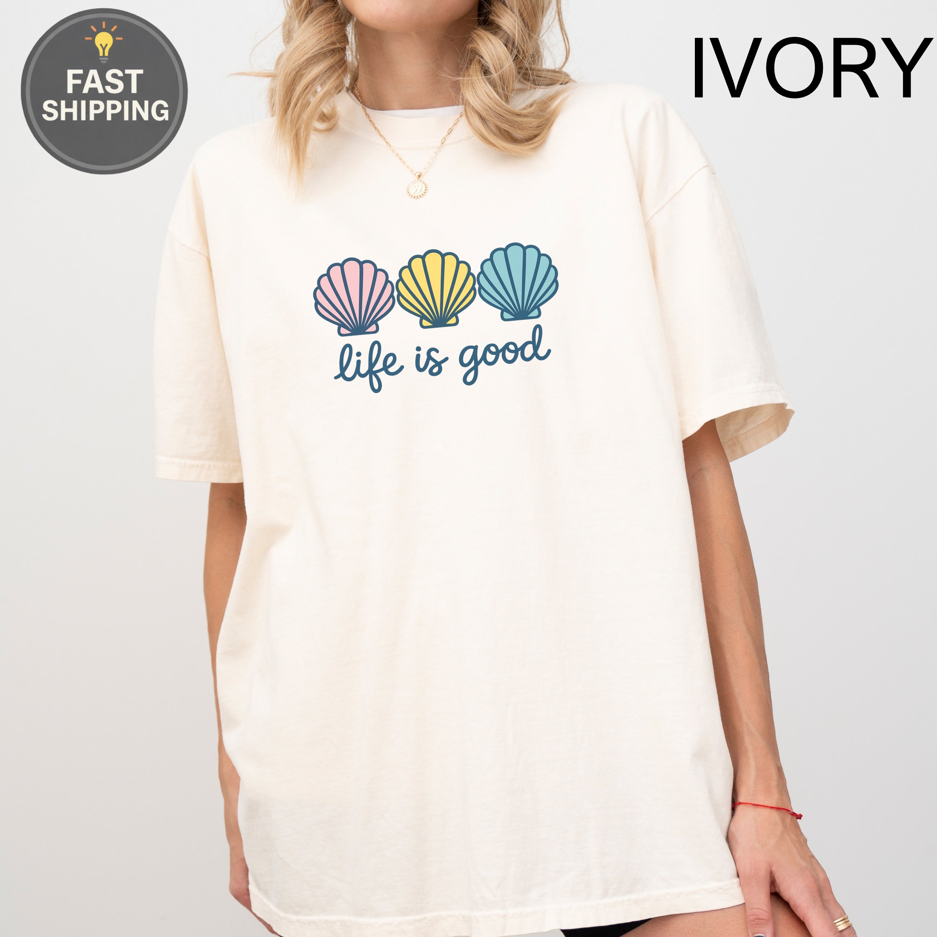 Cream t-shirt with pastel seashells and "life is good" text.