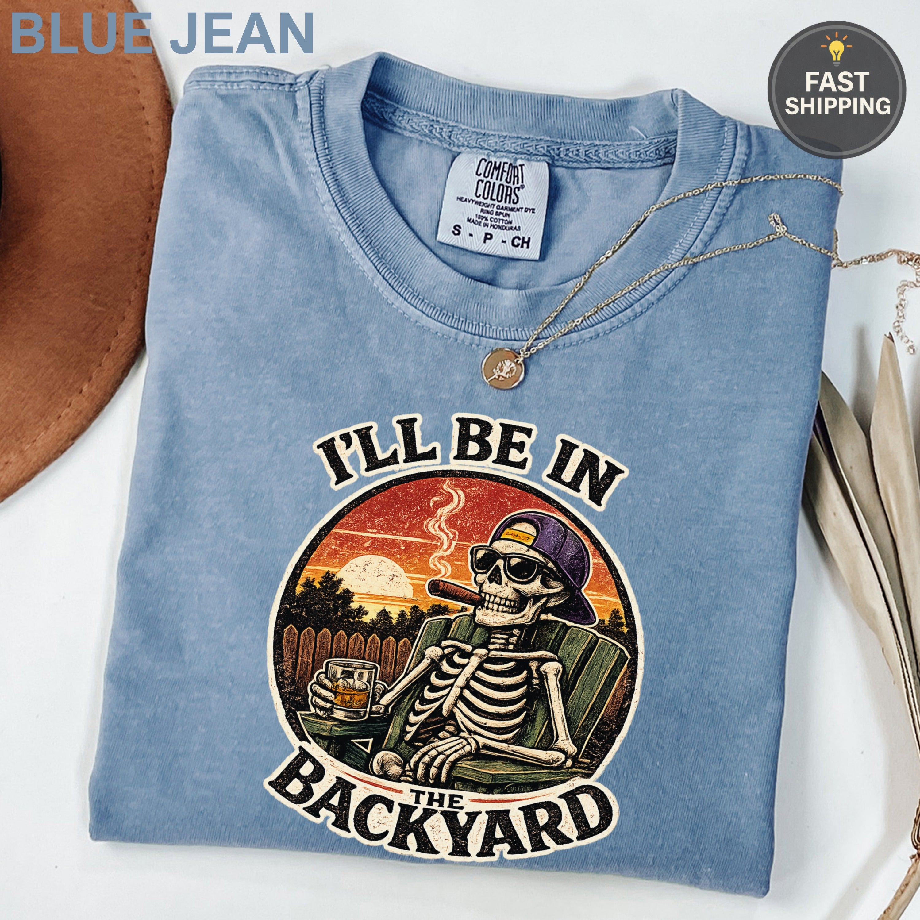 T-shirt with skeleton relaxing in backyard, text "I'LL BE IN THE BACKYARD".