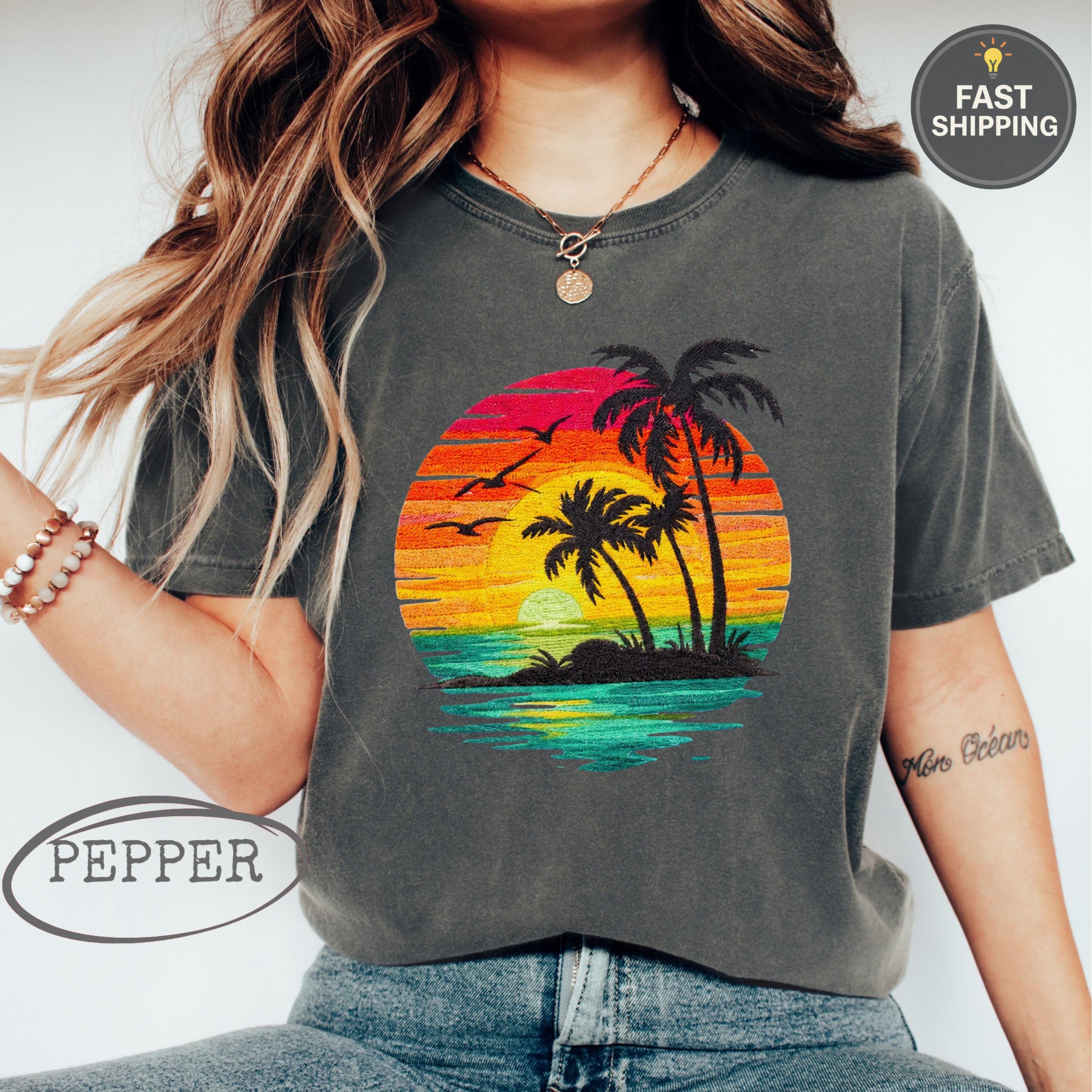 Dark t-shirt with sunset beach scene: palm trees, birds, water, and "Pepper" logo.