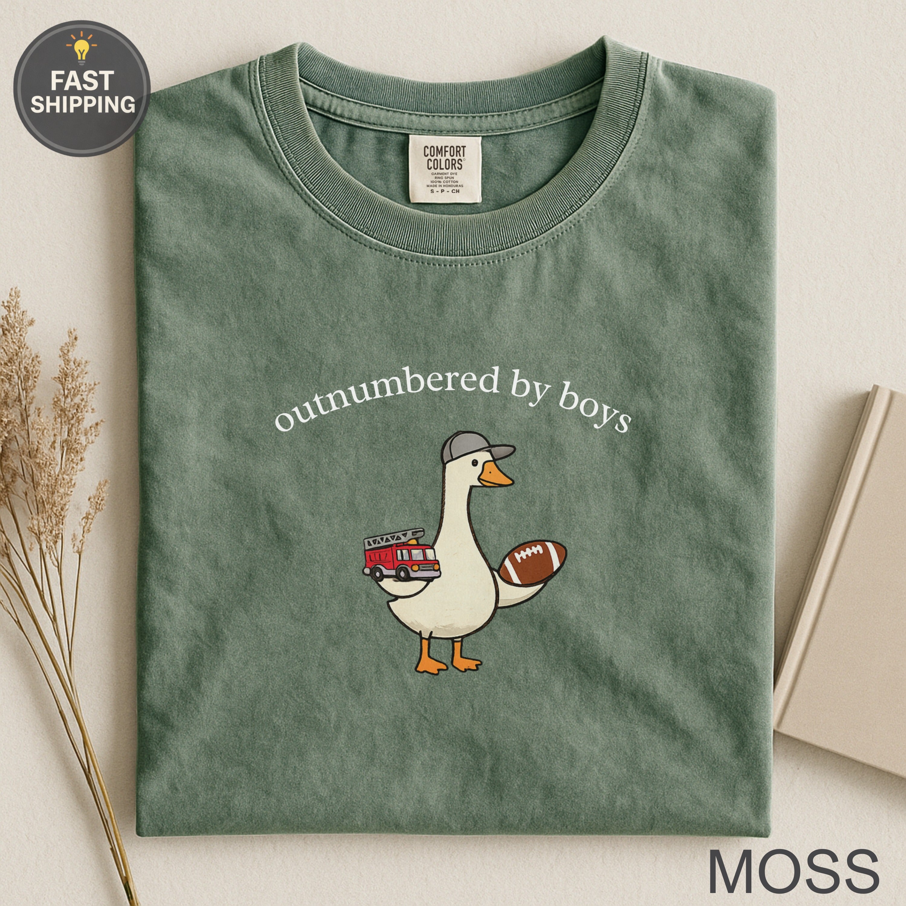 Green t-shirt with duck in firefighter hat holding football, text "outnumbered by boys".