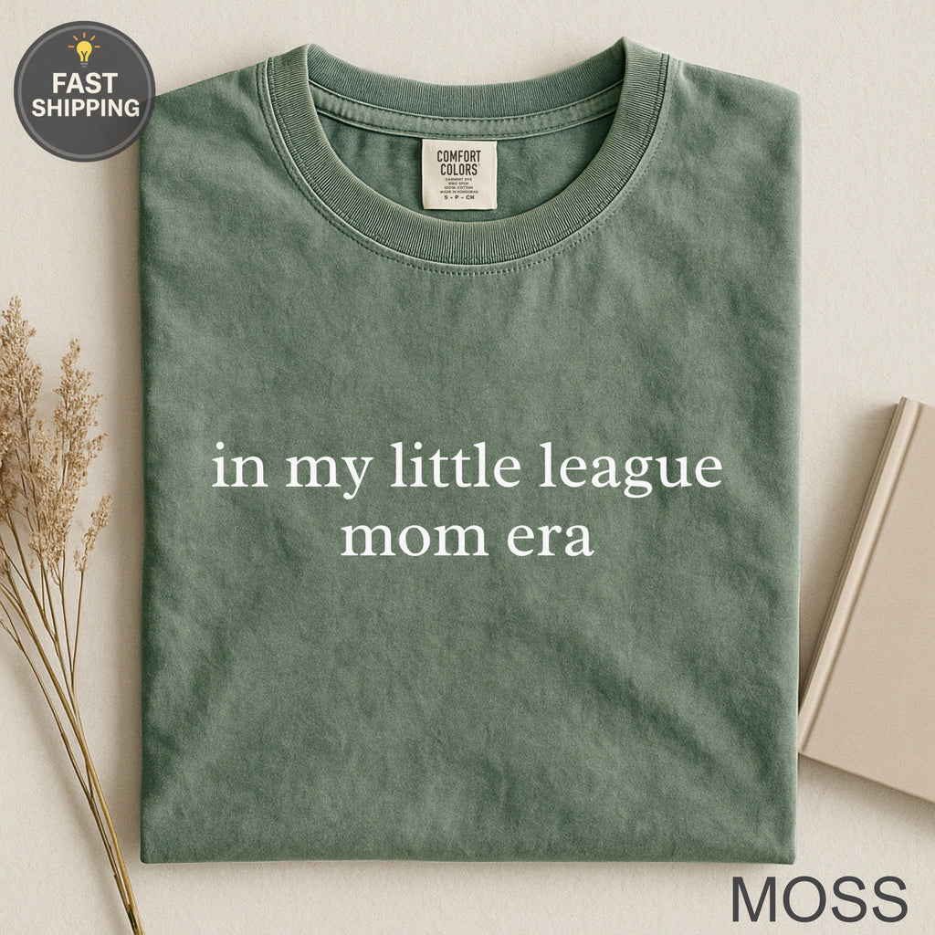 Green t-shirt with "in my little league mom era" text.