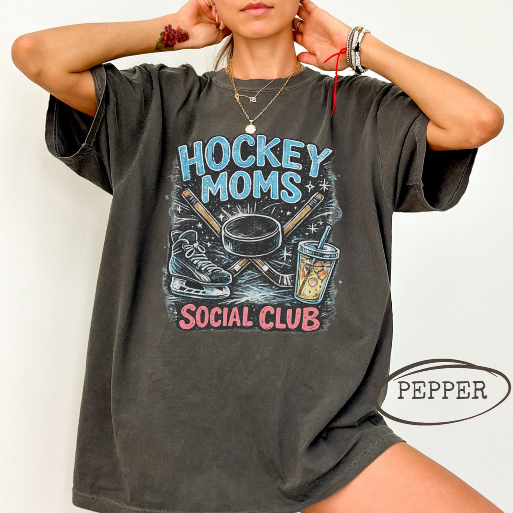 Dark gray t-shirt with "Hockey Moms Social Club" graphic featuring hockey sticks, skates, and drinks.