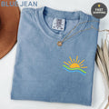 Blue Jean Comfort Colors t-shirt with sun and waves graphic on chest.