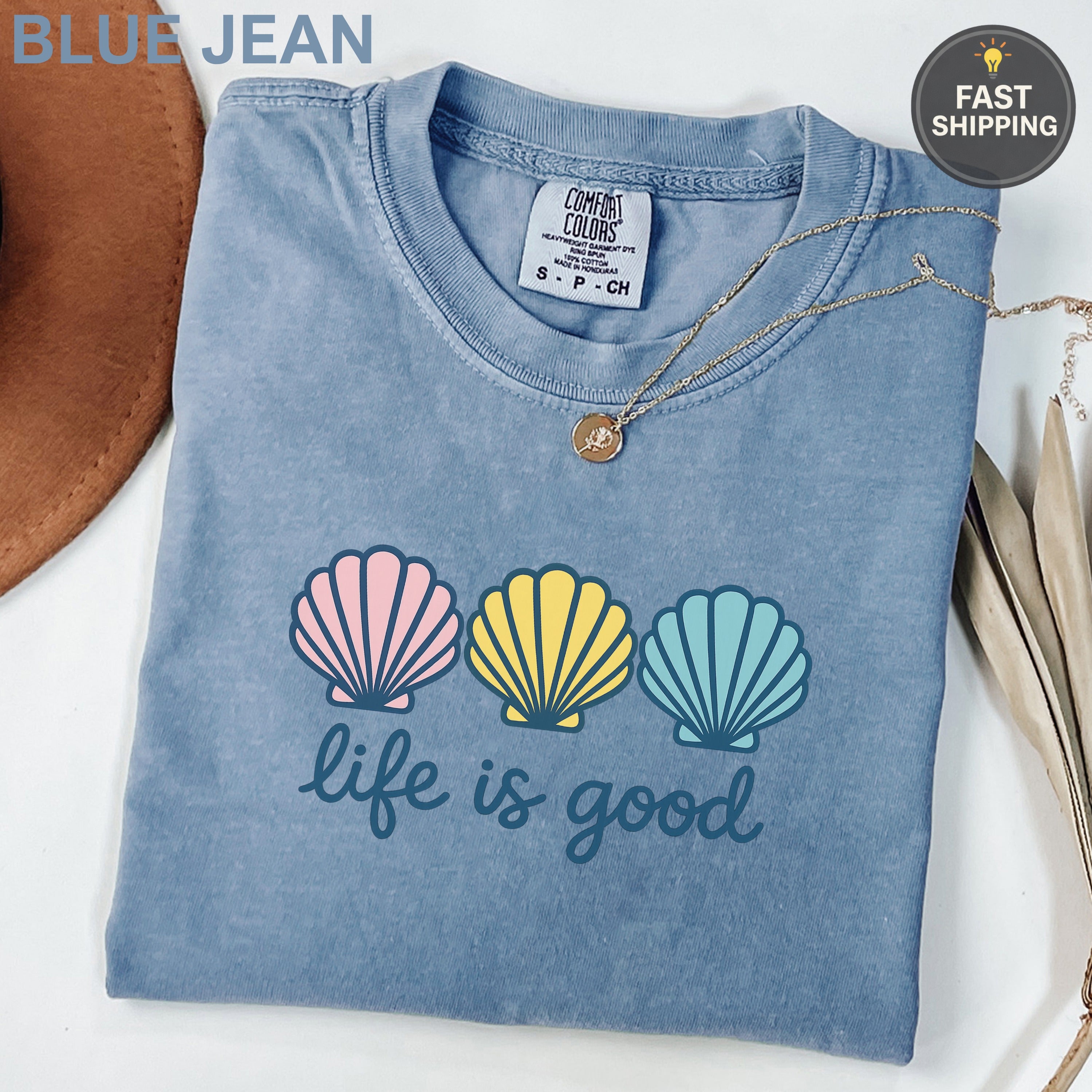 Blue Jean Comfort Colors t-shirt with "life is good" and three seashells.